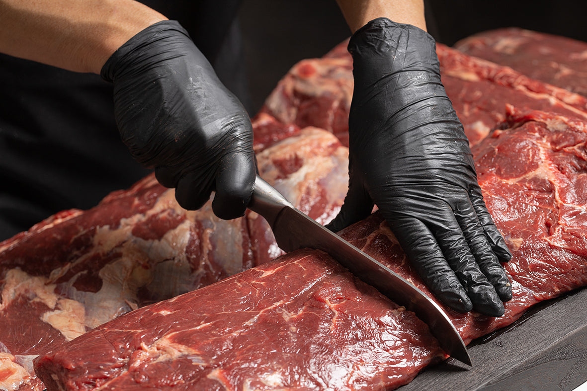 slager snijdt vlees af met zwarte handschoen